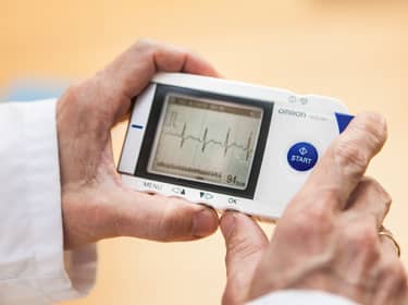 De foto toont de handen van een arts die een digitaal hartfilmpje uitleest