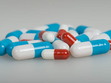 De foto toont een stapel blauw met witte en rood met witte pillen