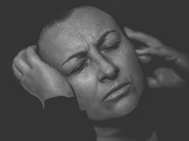 De foto toont een fronsend persoon die haar hoofd vasthoudt