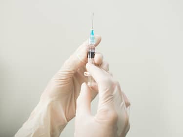 De foto toont een spuit die wordt vastgehouden