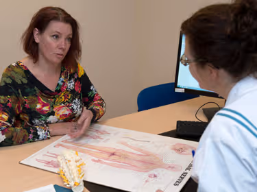 De foto toont een arts en patiënt die een afbeelding van het menselijk lichaam bekijken