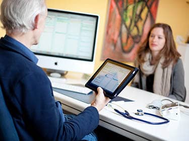 De foto toont een arts in gesprek met een patiënt