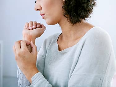 De foto toont een vrouw die jeuk heeft aan haar pols