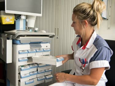 De foto toont een verpleegkundige die bezig is met het klaarleggen van medicijnen