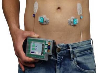 De foto toont een persoon met een elektronisch apparaat in de hand. Op de buik zitten sensoren en draden die verbonden zijn met het apparaat.