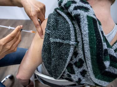 De foto toont iemand die een prik in de bovenarm krijgt