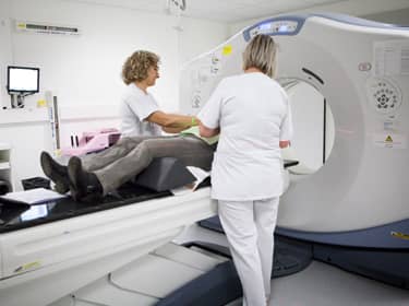 De foto toont verpleegkundigen die assisteren bij een MRI-scan van een patiënt
