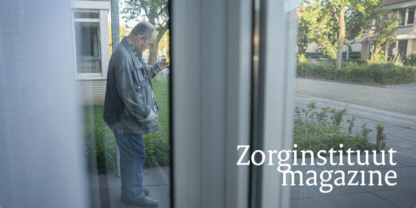 Een verstandelijk gehandicapte man staat in de tuin en kijkt naar zijn hand