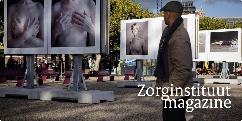 Een man loopt langs een fotografietentoonstelling in de buitenlucht. Op de foto's zijn verschillende vrouwen afgebeeld.