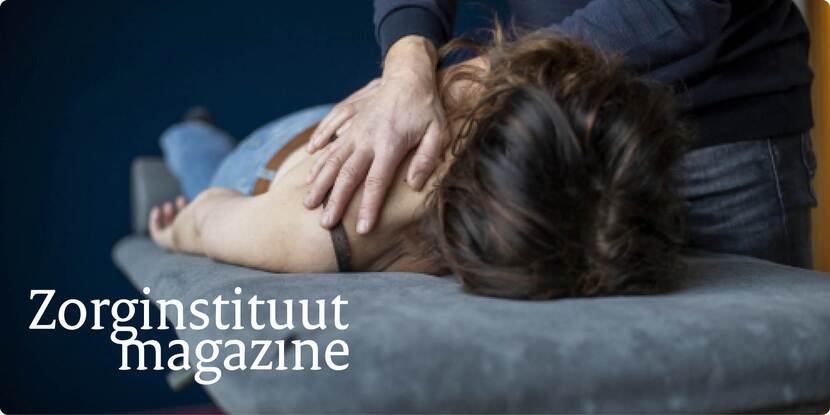 De afbeelding toont een vrouw die op haar buik op een behandeltafel ligt en gemasseerd wordt op haar rug door haar therapeut.
