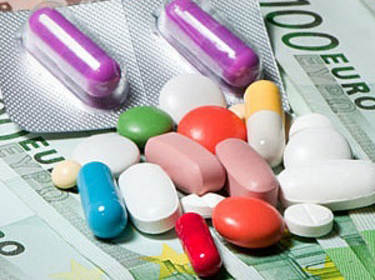 De foto toont een verzameling verschillend gekleurde pillen die op briefjes van 100 euro liggen