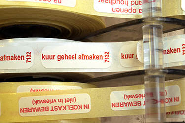 De afbeelding toont stickers voor op geneesmiddelen met de teksten kuur geheel afmaken en IN KOELKAST BEWAREN (niet in vriesvak)