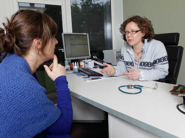 De afbeelding toont een vrouw die in gesprek is met haar huisarts