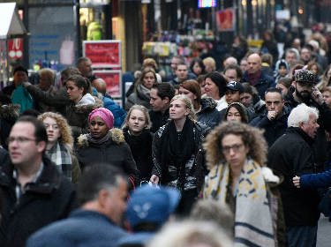 De foto toont een straat met wandelende mensen