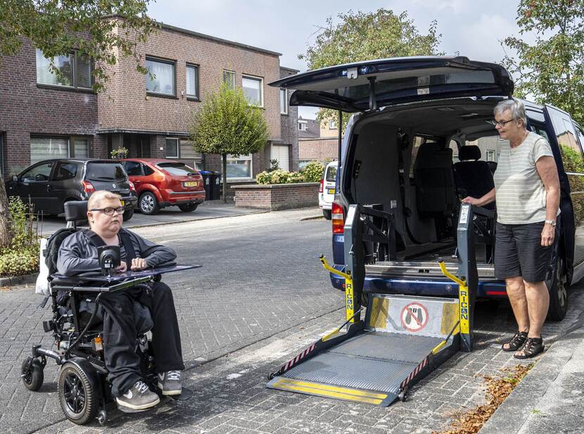 De foto toont links een persoon in een elektrische rolstoel, buiten in een woonwijk. Rechts staat een persoon bij een aangepaste auto waar de rolstoel achterin kan rijden.